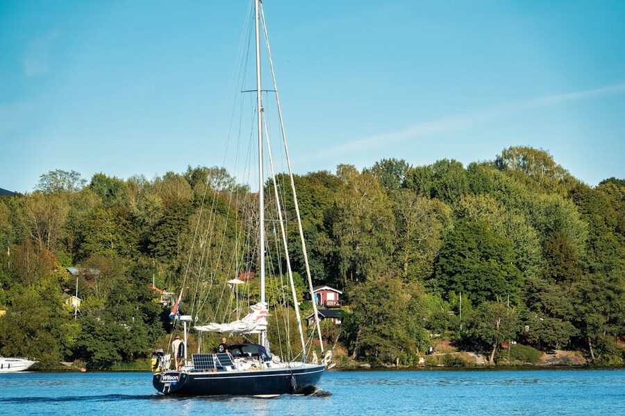 A yacht sails through the calm waters of Stockholm Archipelago surrounded by green islands
