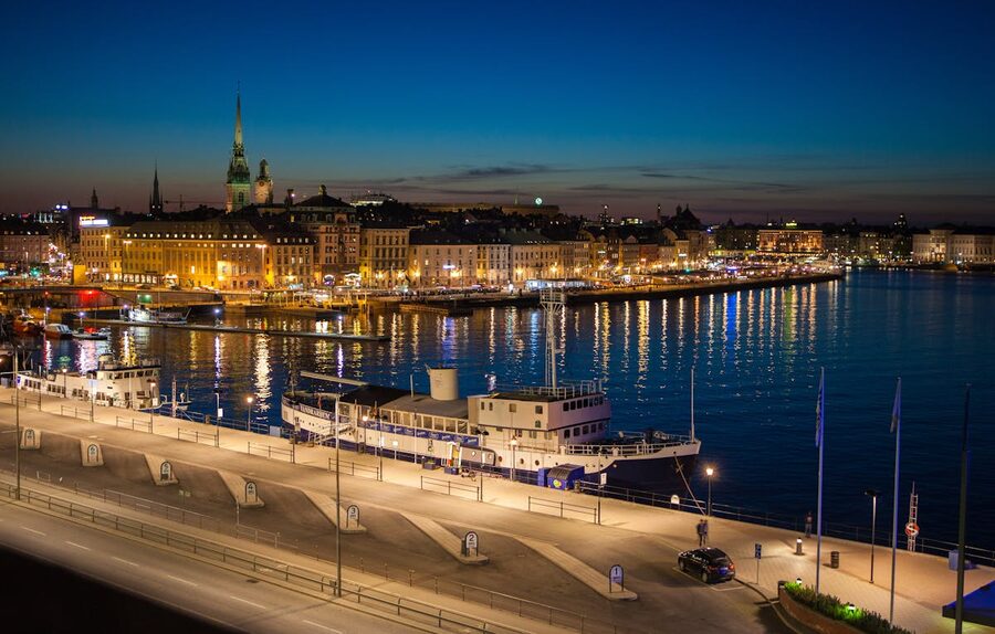 Night view of Stockholm waterfront with illuminated buildings and moored boats