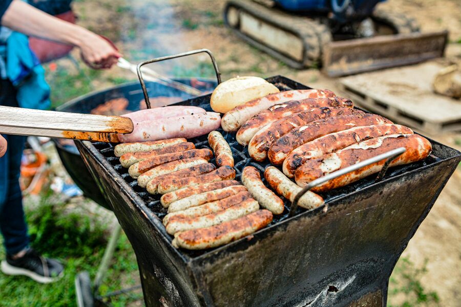 Sausages and bread cooking on an outdoor barbecue grill