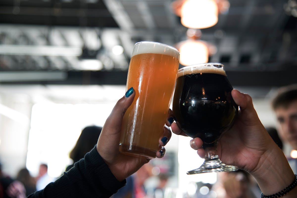 Two people clinking glasses of craft beer in a bar