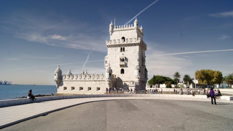 The Belem Tower standing at the edge of the Tagus River in Lisbon under blue skies
