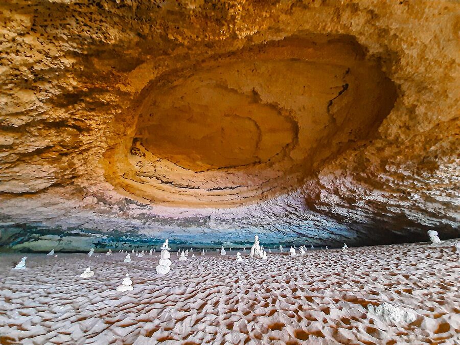 Inside Benagil Cave looking up at the circular oculus opening to blue sky