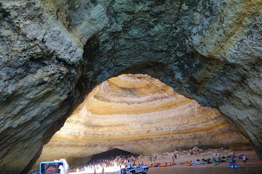 Sandy interior of Benagil Cave with a few visitors inside