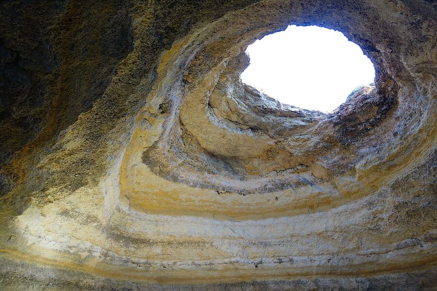 Sunlight streaming into Benagil Cave onto the enclosed beach