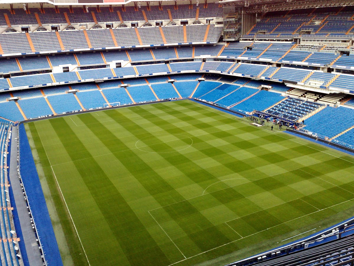 Aerial view of the Bernabeu pitch showing the perfectly trimmed green grass and blue seating