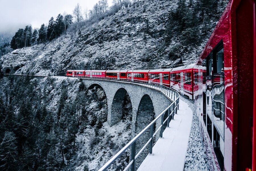 Red Bernina Express crossing snow-covered bridge