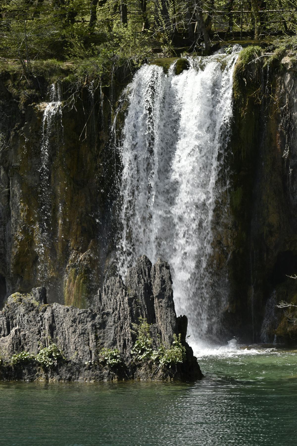 Waterfall in Plitvice Lakes National Park surrounded by lush spring greenery