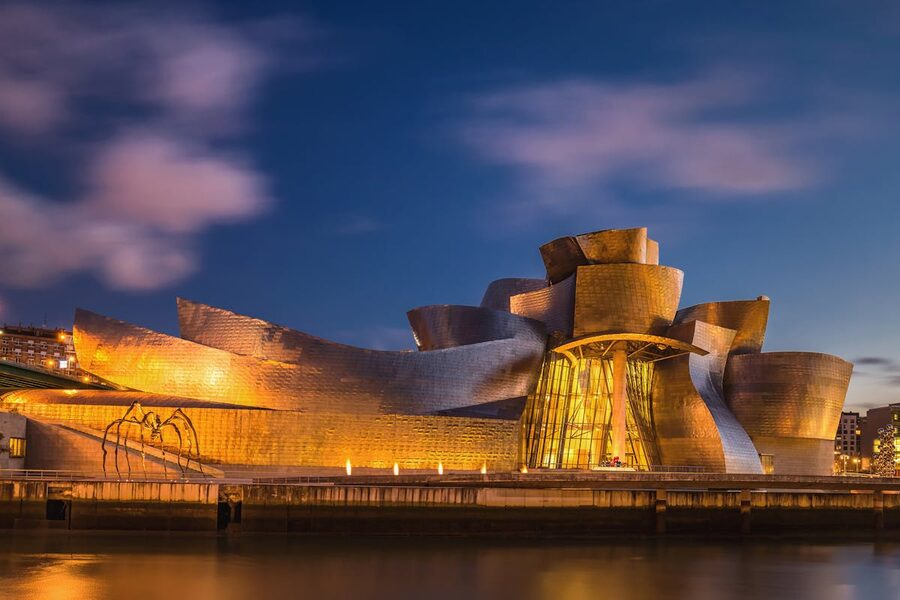 The Guggenheim Museum in Bilbao illuminated against the evening sky