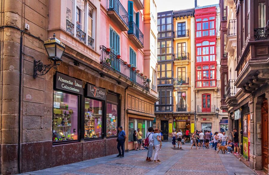 A lively street in Bilbao old town lined with colorful buildings and people walking in the sunshine