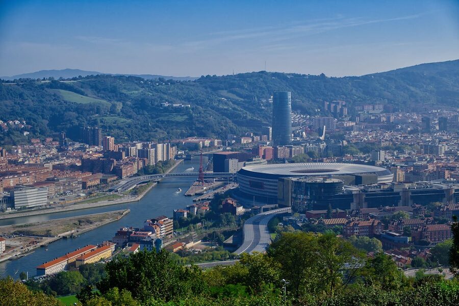 View across Bilbao showing San Mames Stadium and the Iberdrola Tower against a mountain backdrop