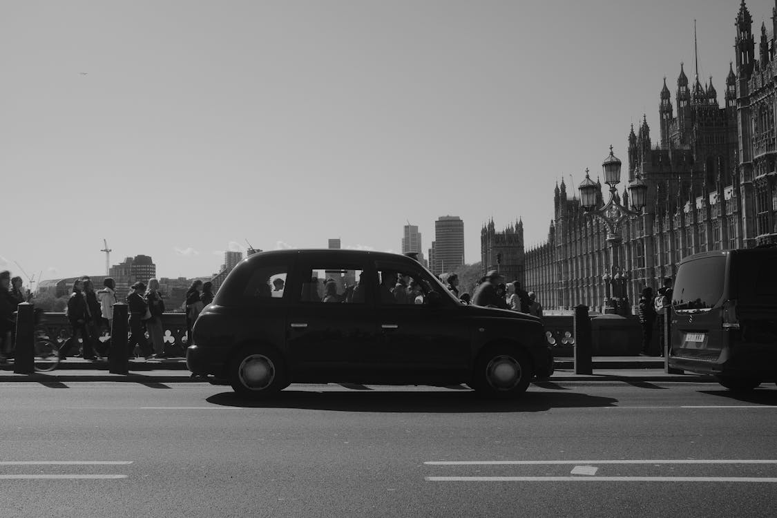 Black London taxi cab passing Westminster Bridge with Houses of Parliament in background