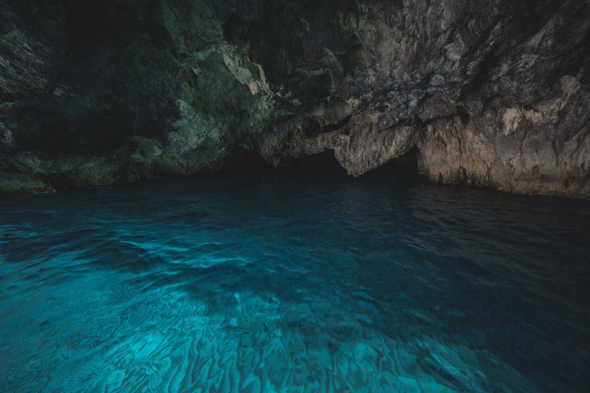 Calm blue water illuminated by natural light inside a sea cave