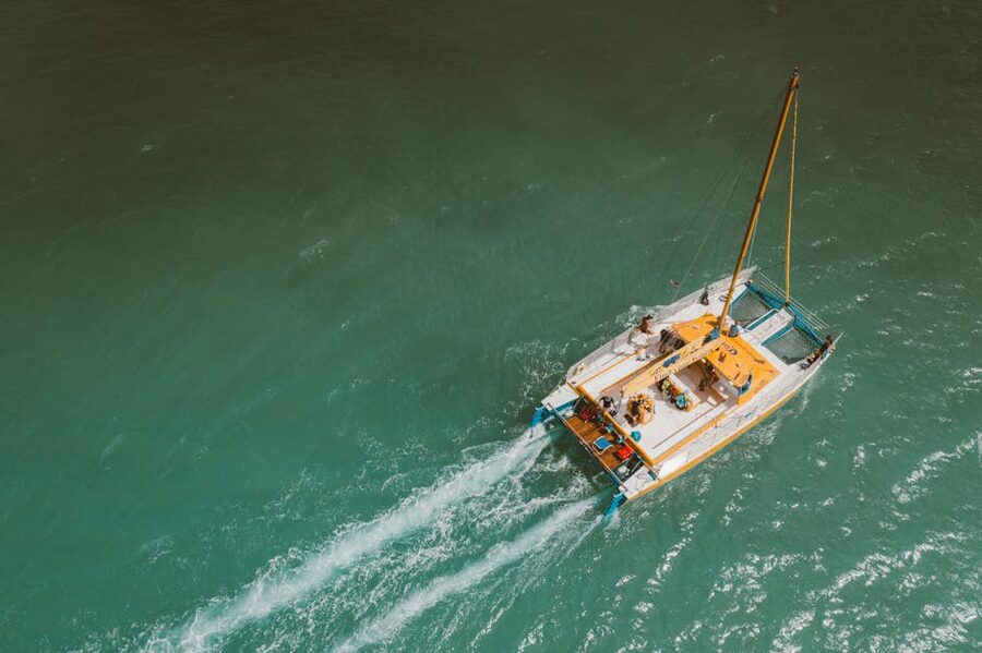 Yacht sailing in turquoise sea with passengers on deck