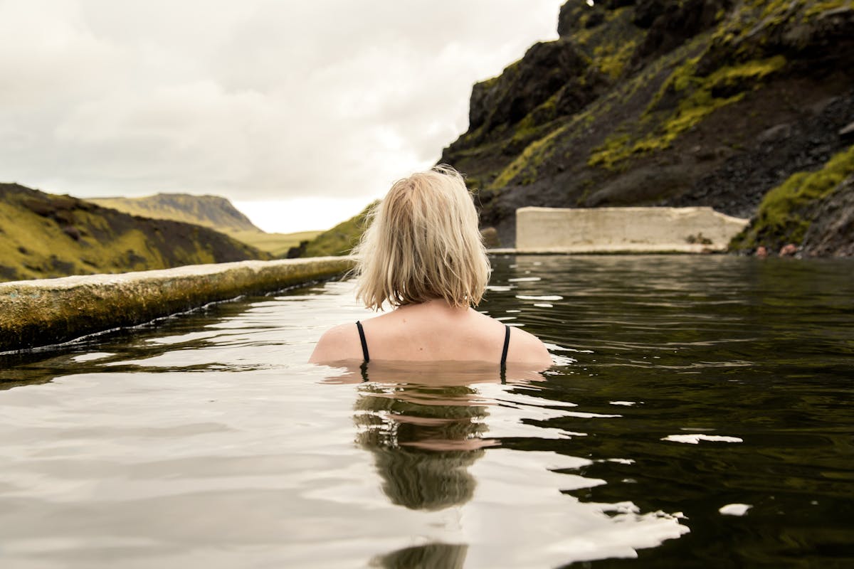 Woman enjoying a warm dip in a scenic Icelandic geothermal pool
