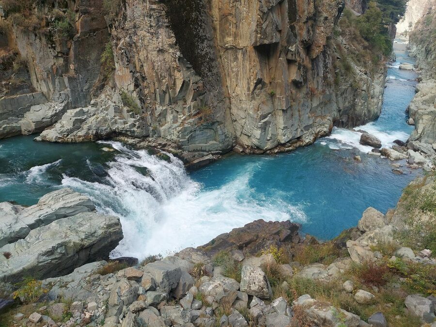 Blue river flowing through a dramatic canyon between towering rocky cliffs