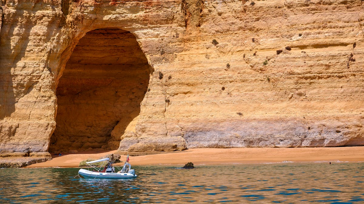 A tour boat cruising near eroded golden cliffs along the Algarve coast in Portugal