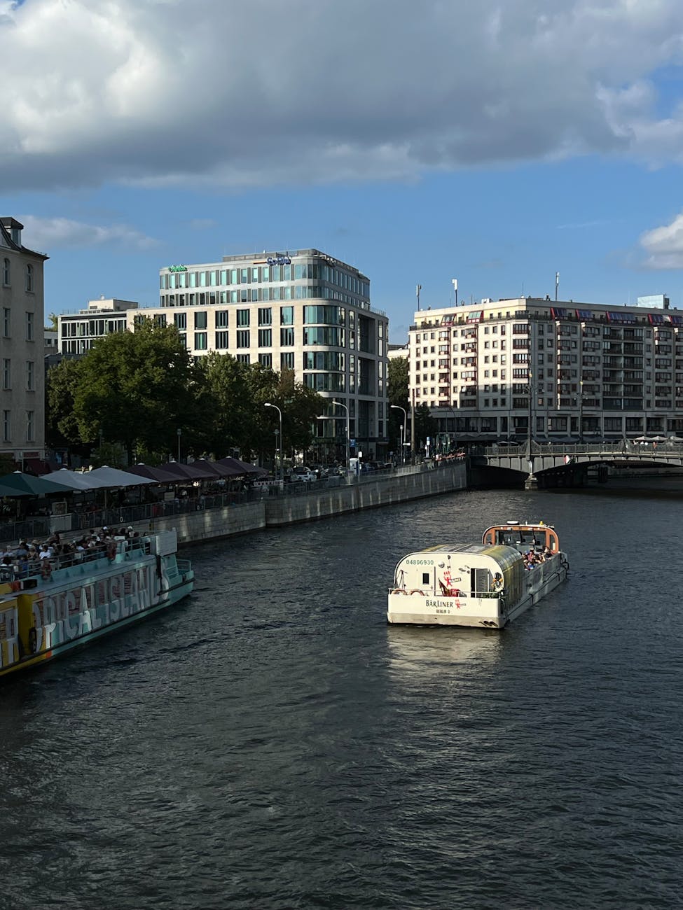 A sightseeing boat passing modern glass buildings on the Spree River in Berlin