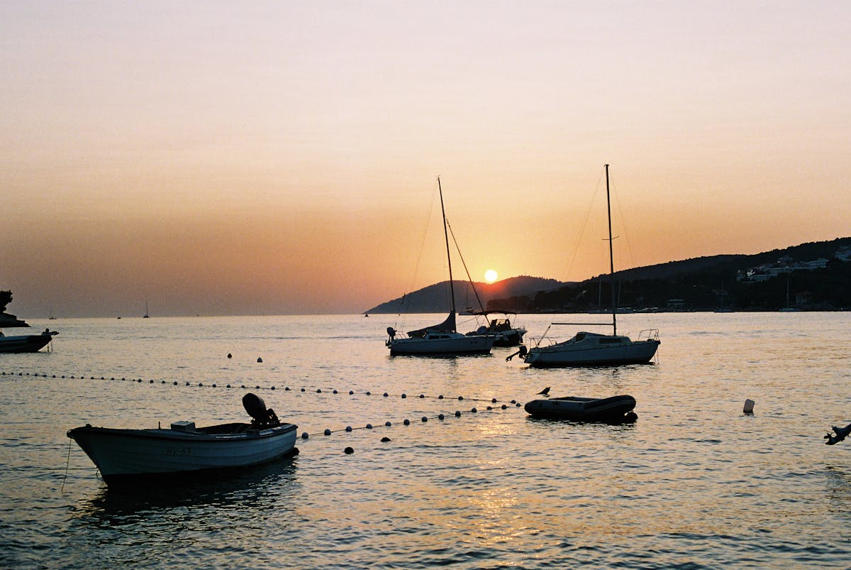 Boats silhouetted on calm sea at sunset