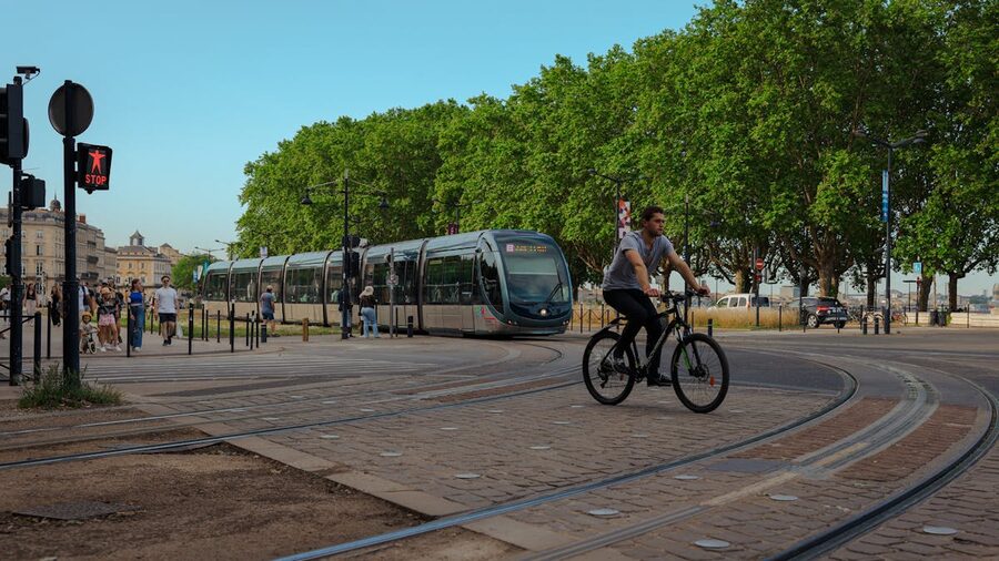 Cyclist passing a tram on a Bordeaux city street