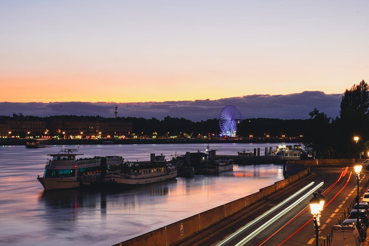 Evening view of Bordeaux riverside with illuminated ferris wheel and boats