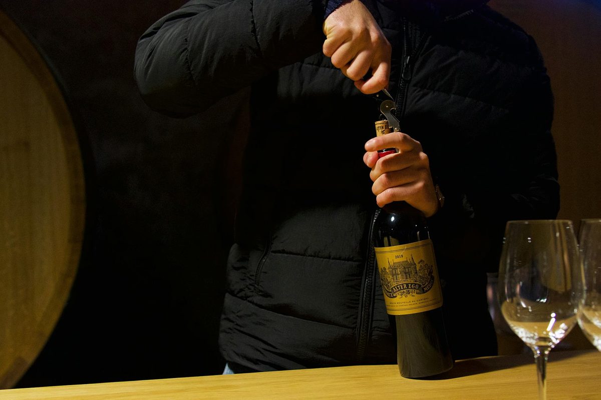 Person uncorking a wine bottle at a tasting room in Margaux Bordeaux