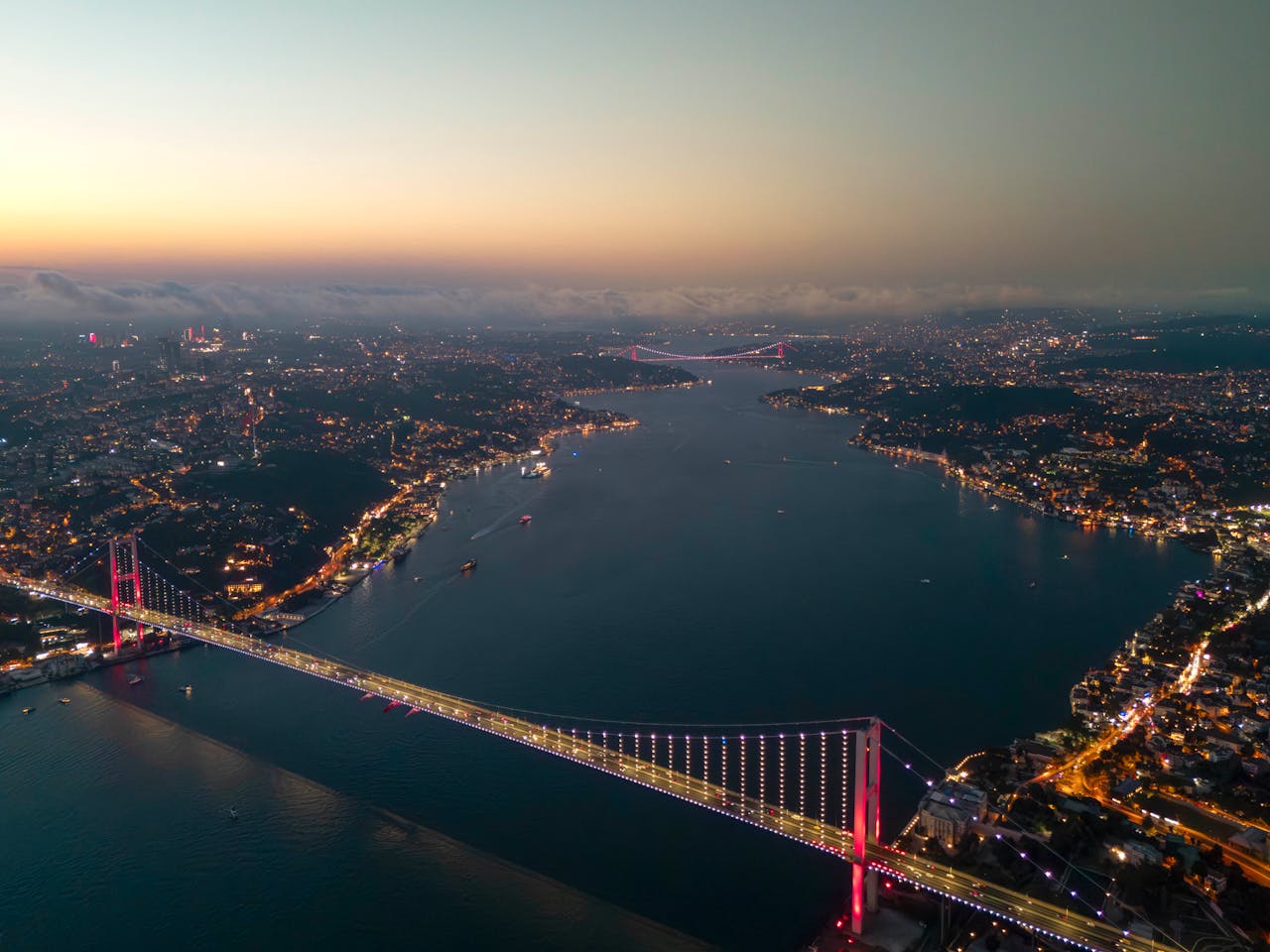 Aerial view of the Bosphorus Bridge lit up at twilight with Istanbul stretching out on both sides