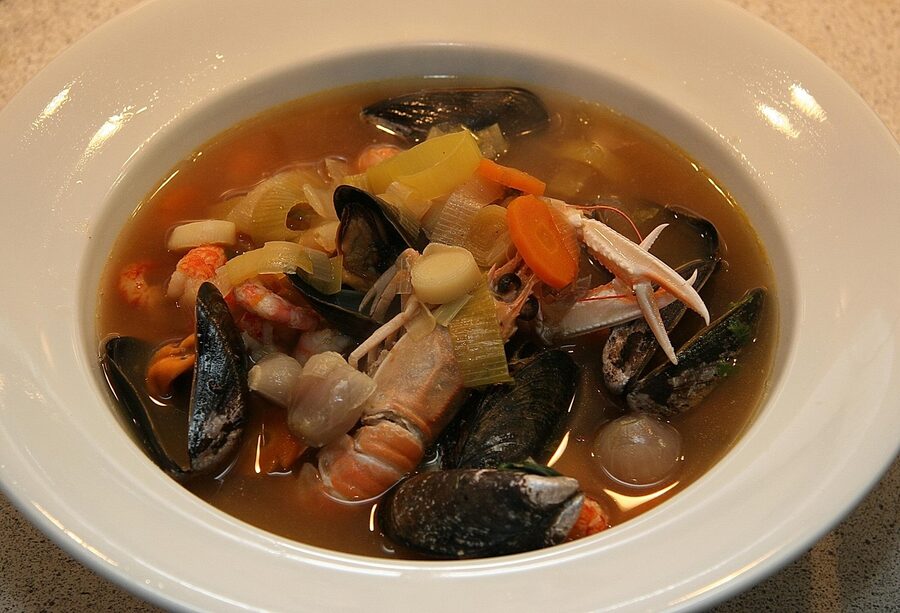 Traditional bouillabaisse fish soup with mussels lobster and vegetables in a white bowl