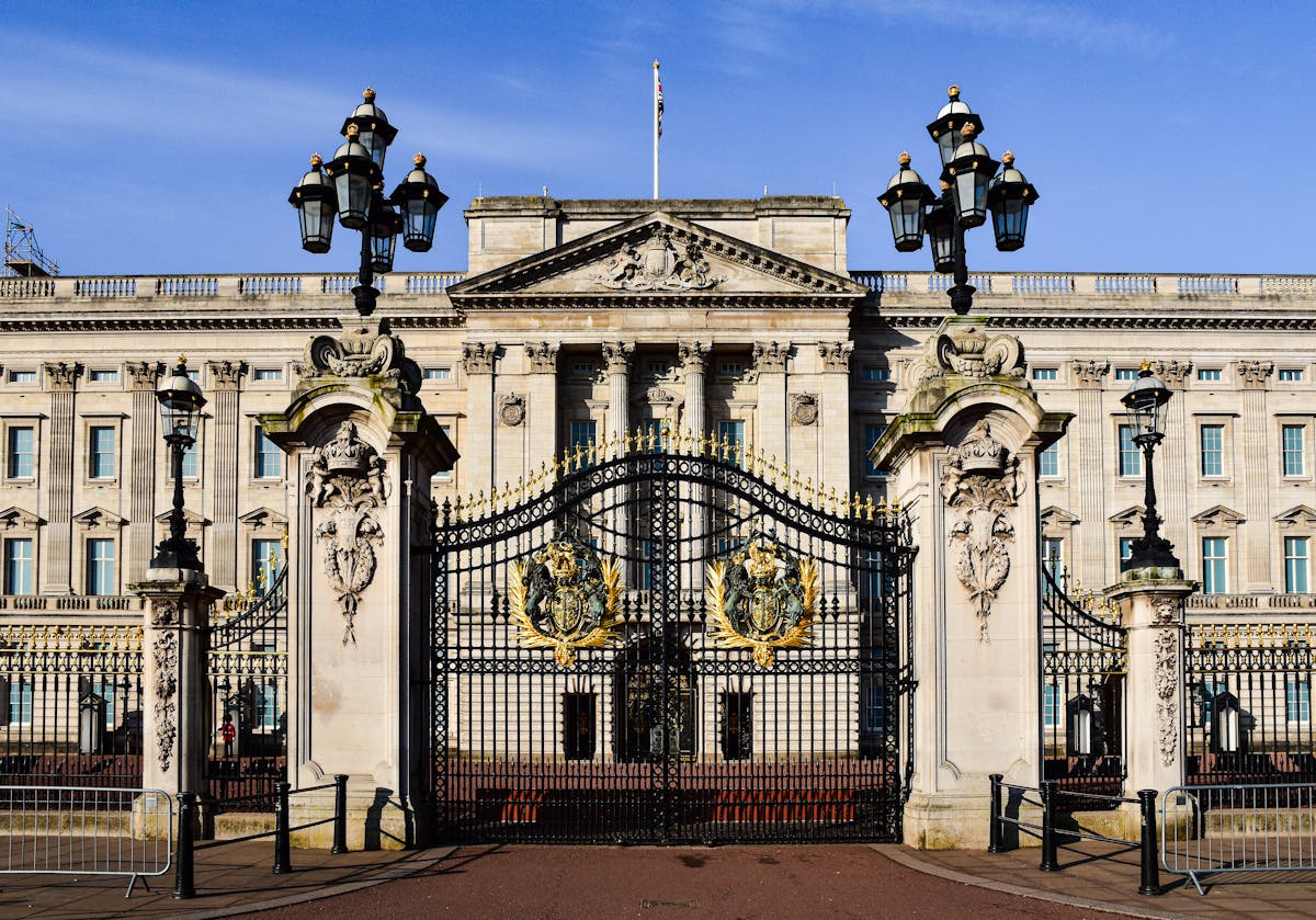 Buckingham Palace front facade seen through ornate iron gates