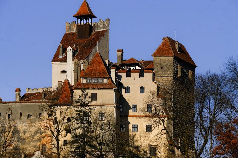 Bran Castle with red roofs under autumn sunlight and clear blue sky