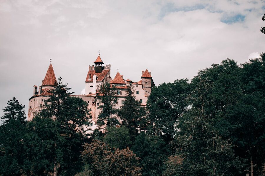 Bran Castle rising above trees in the Transylvanian landscape