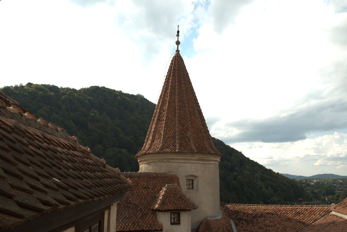 Bran Castle iconic tower with surrounding lush hills under bright sky