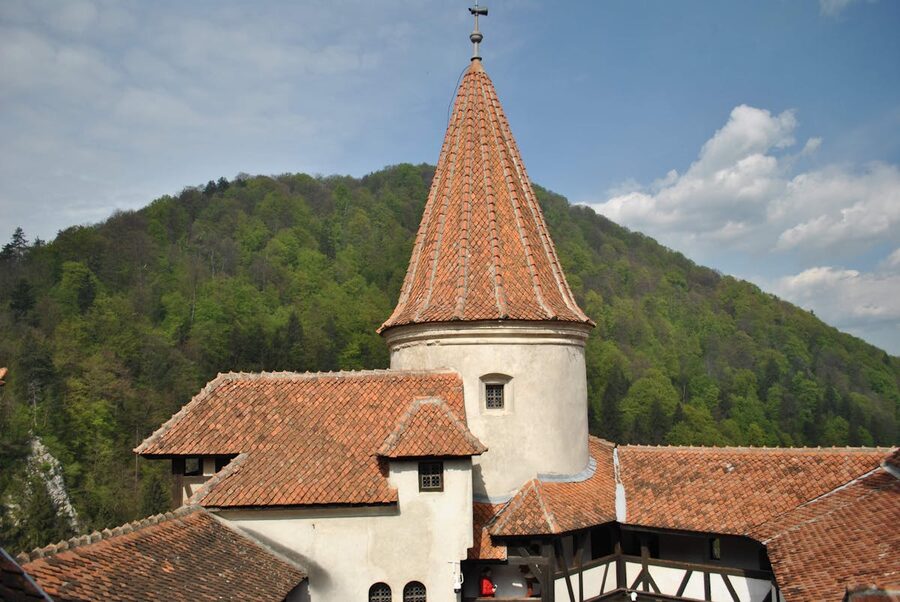 Tower of Bran Castle with green forested hills behind