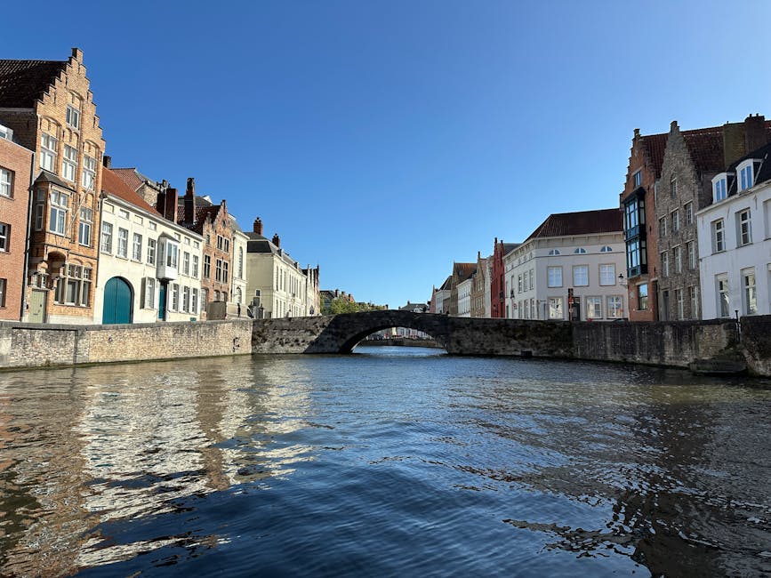 Bruges stone bridge over a canal under a clear blue sky