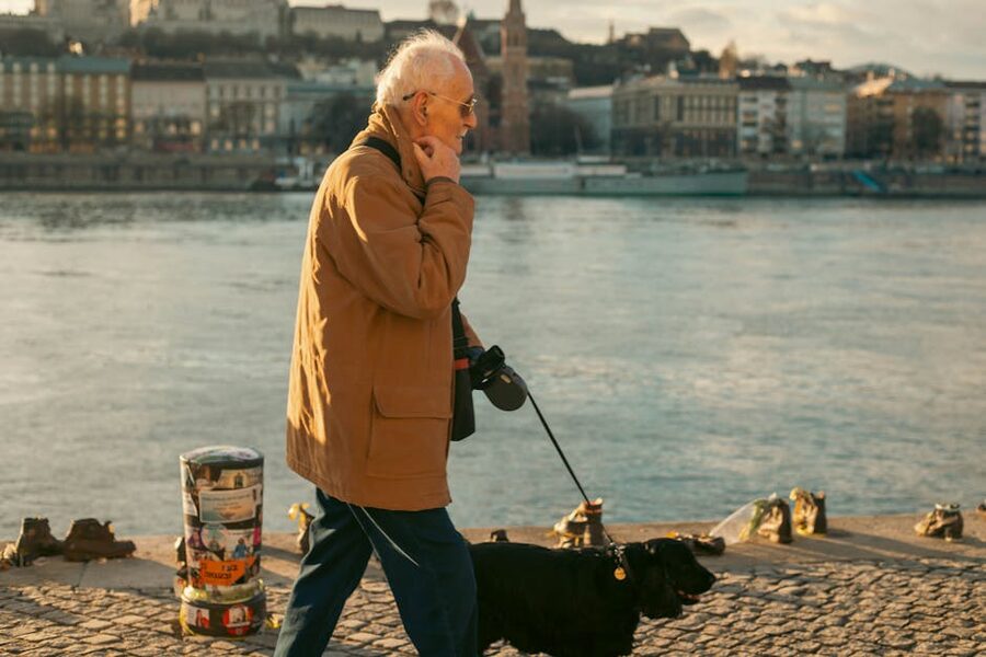 Elderly man walking his dog along the Danube River in Budapest