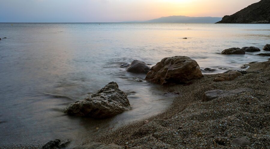 Sunset over Cabo de Gata beach with rocky formations in the foreground