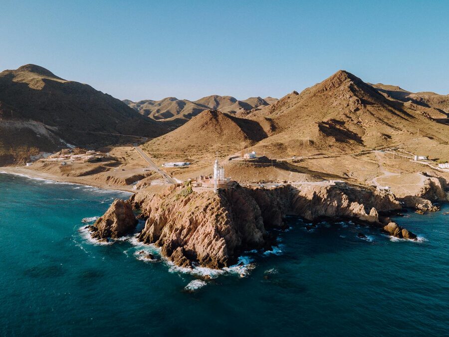 Lighthouse perched on volcanic cliffs at Cabo de Gata with mountain backdrop