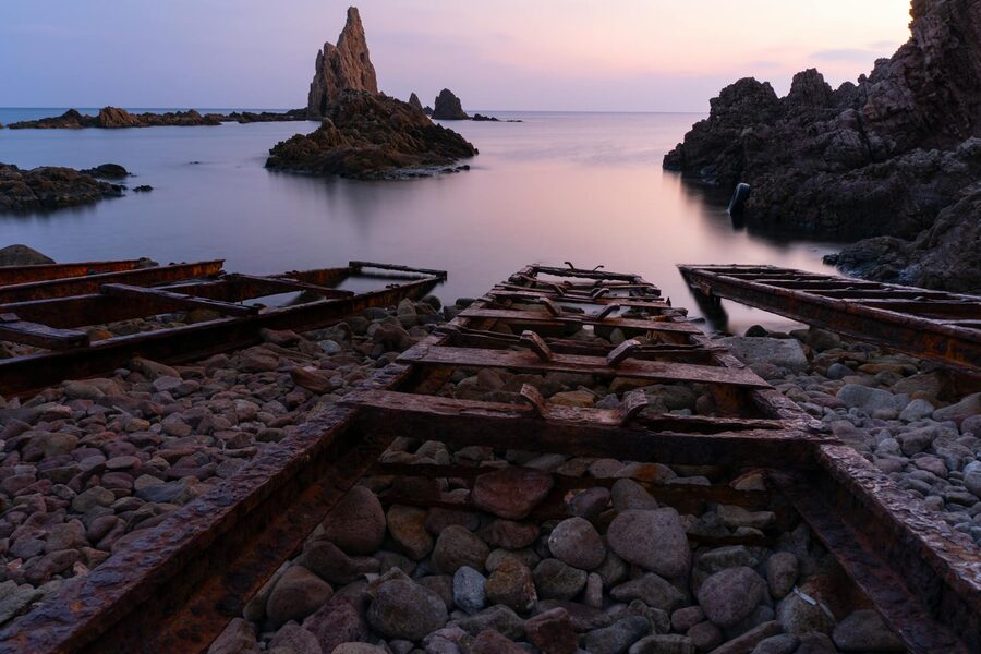 Twilight over Cabo de Gata rocky shoreline with old iron rails