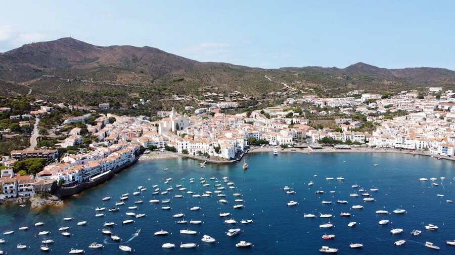 Aerial view of the whitewashed town of Cadaques on the Costa Brava with sailboats in the bay