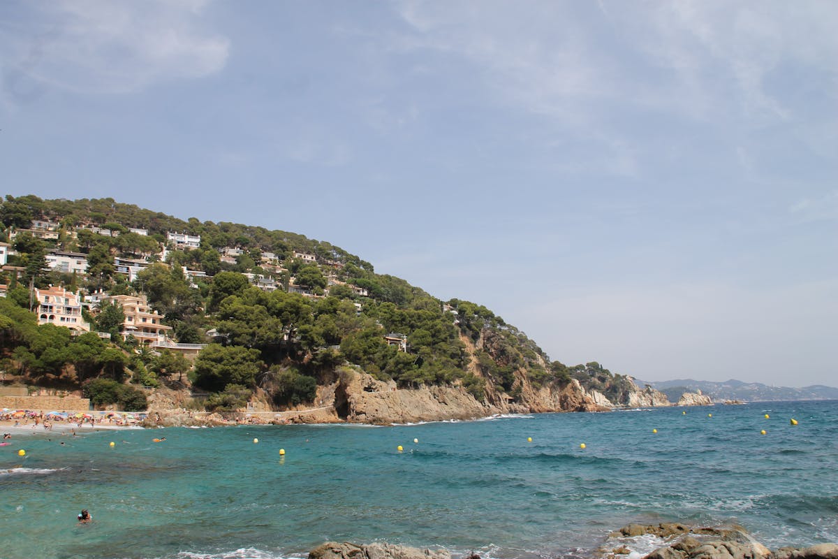 Tranquil seaside scene at Cala Canyelles with clear blue waters and lush greenery