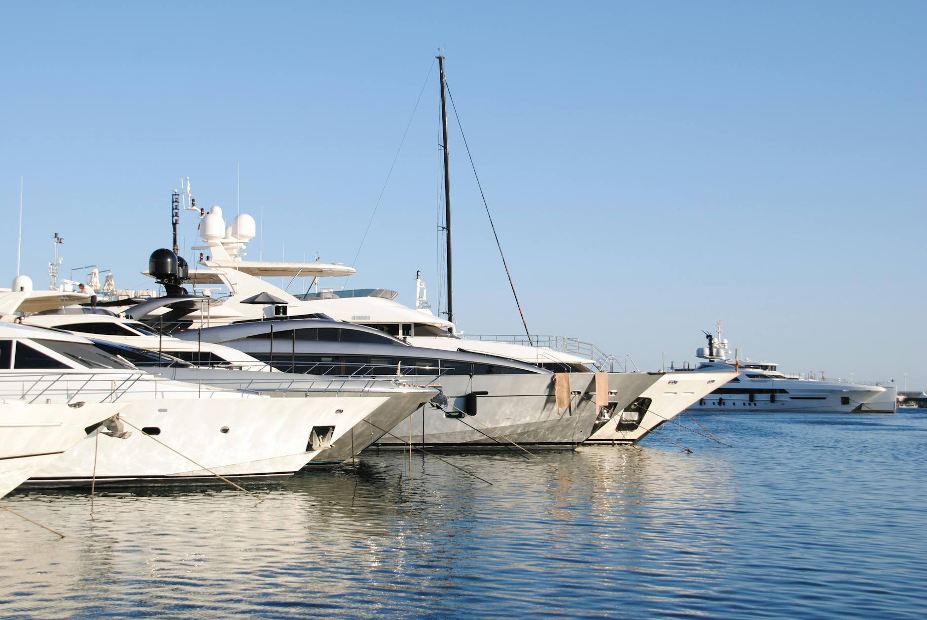 Large luxury yachts moored in the Cannes marina with the Le Suquet hill behind