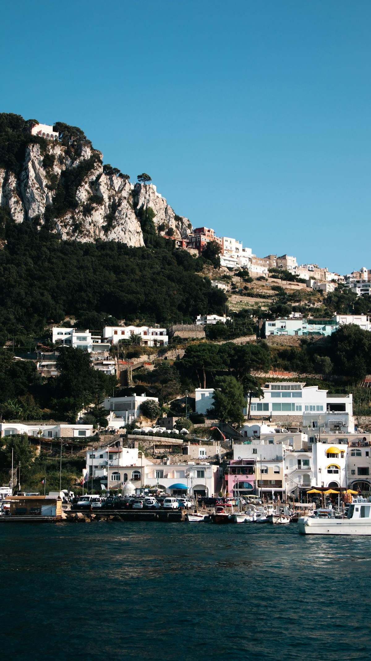 Colorful buildings perched on a green hillside along the coastline of Capri Italy