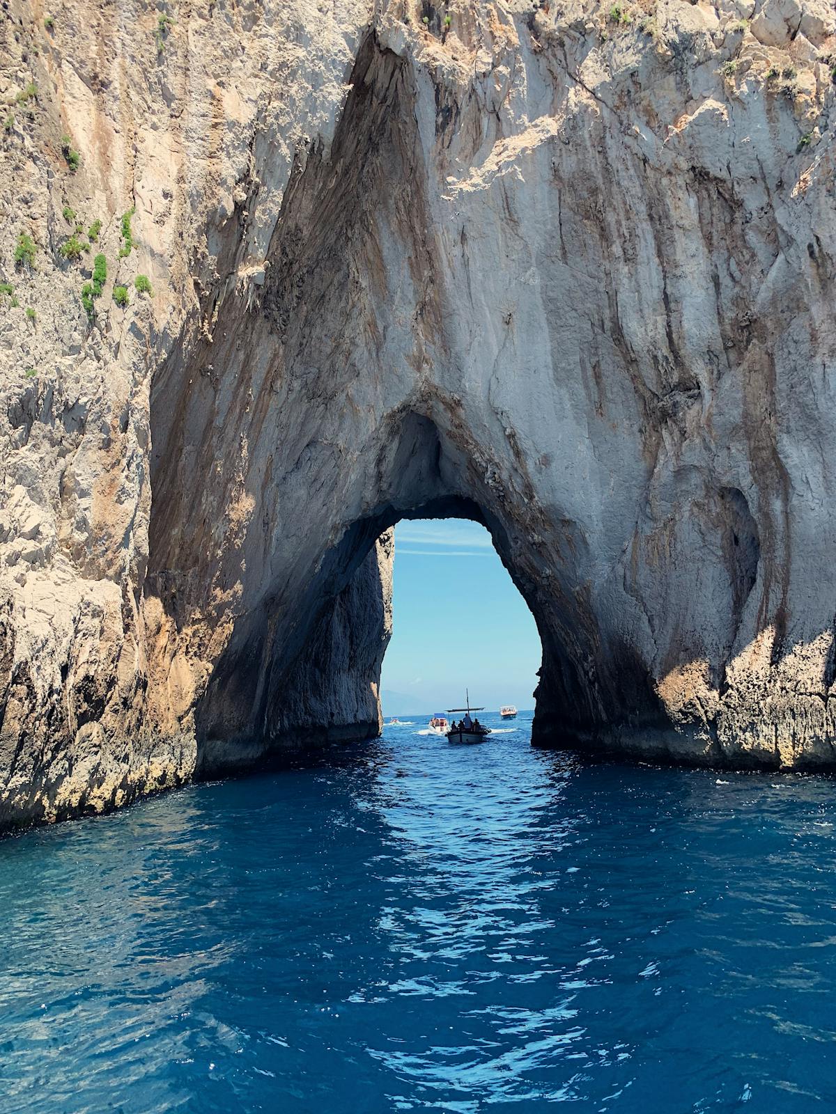 A natural stone arch formation over turquoise water near the island of Capri