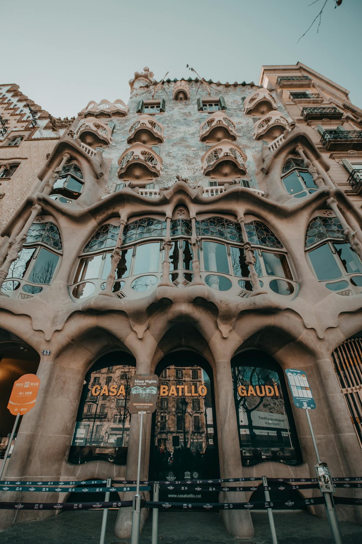 Casa Batllo photographed from a low angle showing the full height of the facade against a Barcelona sky