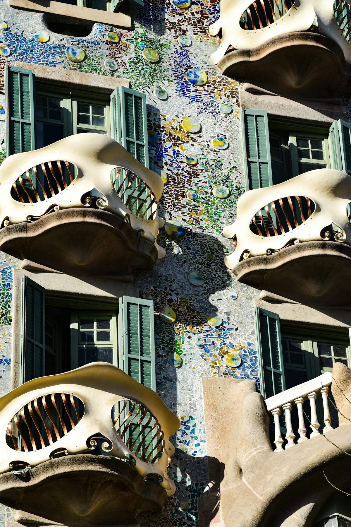 Close-up of Casa Batllo mosaic balconies with their skull-like iron railings and broken ceramic tile decoration