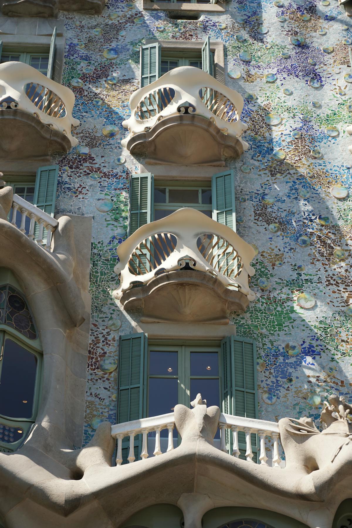 Ornate facade detail of Casa Batllo showing the layered ceramic tiles and flowing window frames