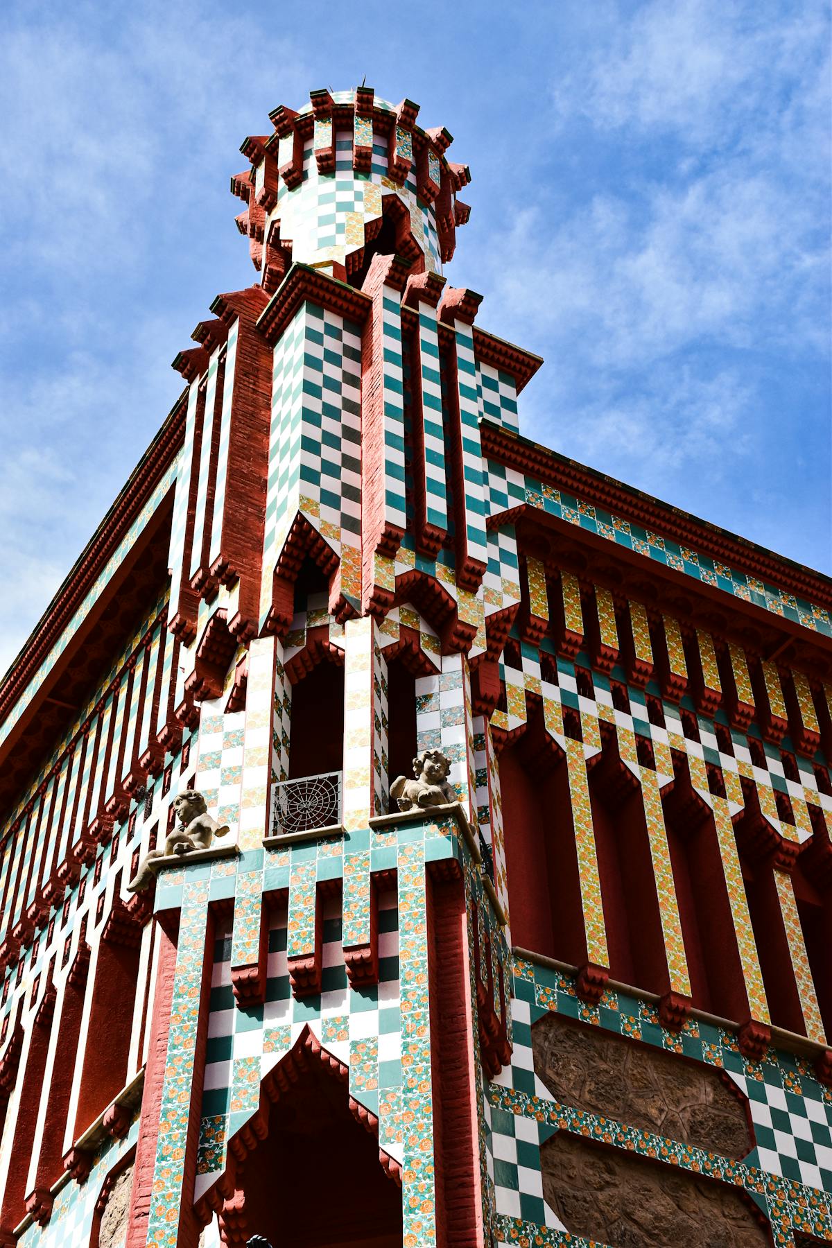 Exterior view of Casa Vicens showing the distinctive green and white tile facade against Barcelona sky