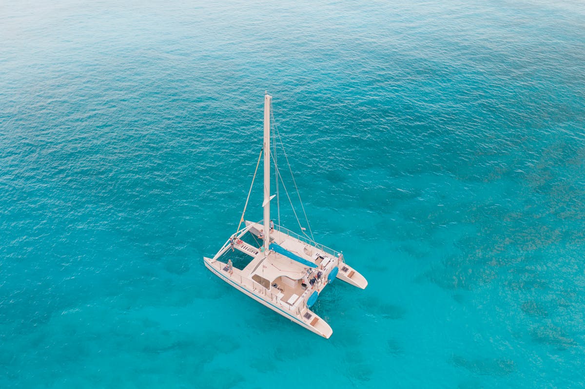 Aerial view of a catamaran sailing through crystal clear turquoise waters off the coast of Mallorca