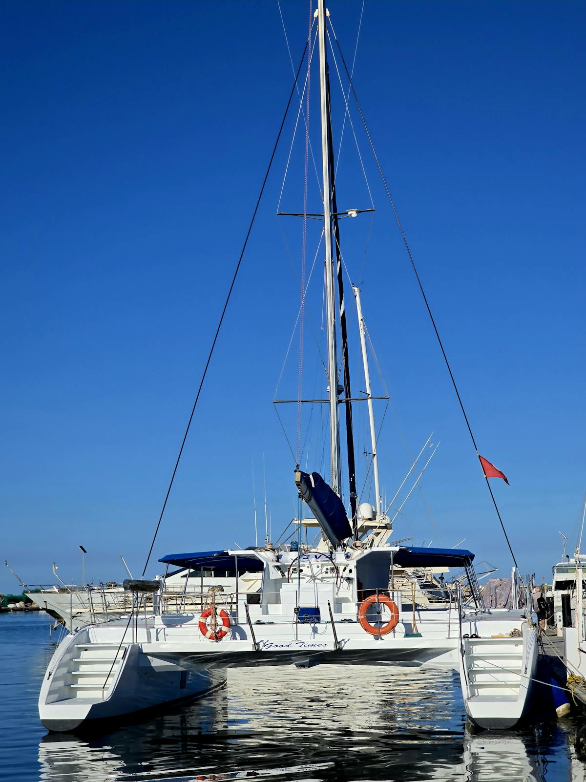 White catamaran docked at a marina under bright blue sky