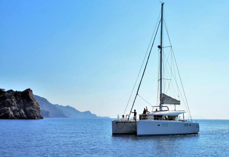 White catamaran sailing on calm turquoise Mediterranean waters