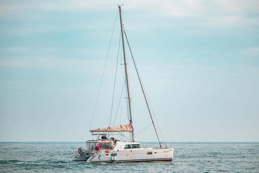 Catamaran sailing peacefully on the sea under a pastel sunset sky
